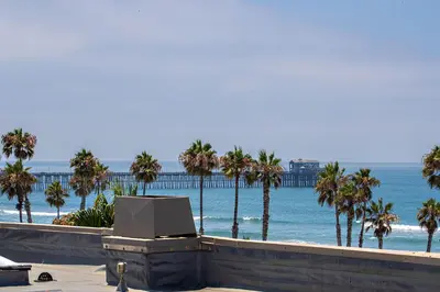 a view of a beach with palm trees and the ocean at Penthouse Condo w/ Panoramic Ocean Views at Beach Resort in Oceanside