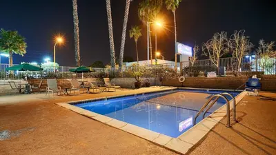 a swimming pool at night with tables and umbrellas at Best Western Poway/San Diego Hotel in Poway