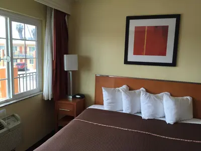 a hotel room with a bed with white pillows and a window at Howard Johnson by Wyndham San Diego Sea World in San Diego
