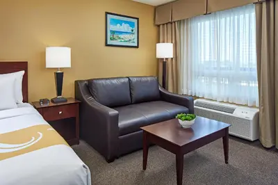 a hotel room with a bed and a leather chair at Comfort Inn Encinitas Near Legoland in Encinitas