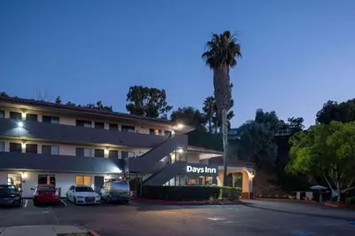 a hotel with cars parked in a parking lot at Days Inn by Wyndham Encinitas Moonlight Beach in Encinitas