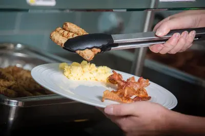 a person is getting food from a plate of food at Ocean Park Inn in San Diego