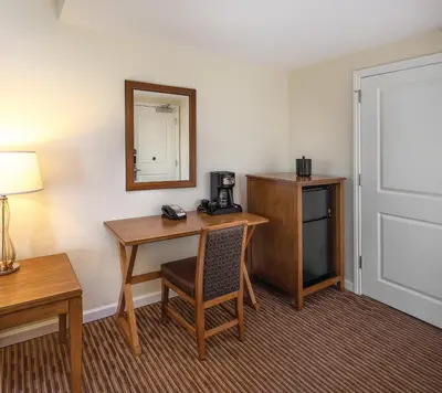 a hotel room with a desk and a mirror at Club Wyndham Oceanside Pier Resort in Oceanside