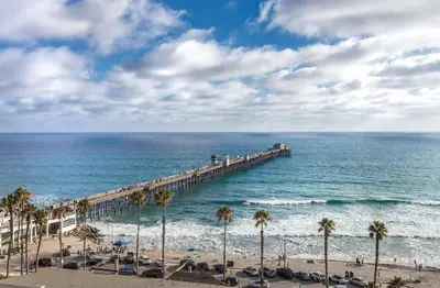 a pier stretches out over the ocean with palm trees at Club Wyndham Oceanside Pier Resort in Oceanside
