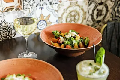 a table with a bowl of food and a glass of wine at The Cassara Carlsbad, Tapestry Collection By Hilton in Carlsbad