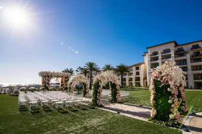 an aisle with white chairs and flowers in front of a building at Waldorf Astoria Monarch Beach Resort & Club in Dana Point