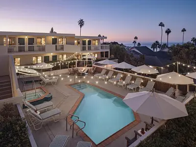 a pool with chairs and umbrellas in front of a building at Laguna Beach House in Laguna Beach