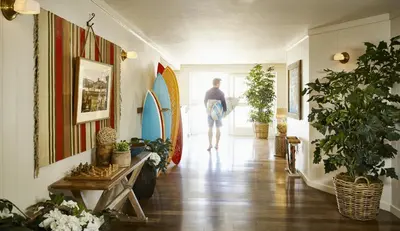 a man walking down a hallway with a surfboard at Laguna Beach House in Laguna Beach
