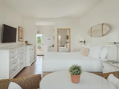 a white bedroom with a large bed and a tv at Laguna Beach House in Laguna Beach