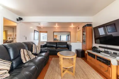 a living room with a black leather couch and a table at Newport Beach House 1 block from the beach FREE pickleball courts and 6 beach cruisers in Newport Beach