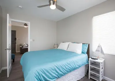 a bedroom with a blue bed and a ceiling fan at MB Jamaica FLAT - Steps 2 Mission Beach in San Diego