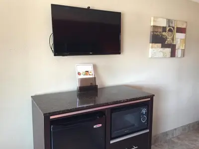 a flat screen tv hanging on a wall with a dishwasher at Harbor Inn & Suites Oceanside in Oceanside