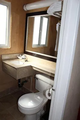 a bathroom with a toilet and a sink and a mirror at Harbor Inn & Suites Oceanside in Oceanside