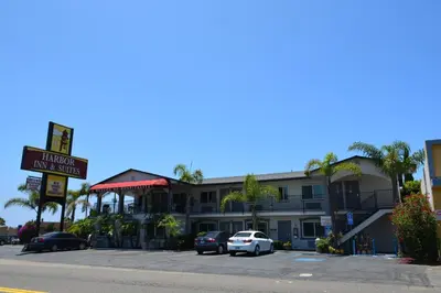 a hotel with cars parked in a parking lot at Harbor Inn & Suites Oceanside in Oceanside