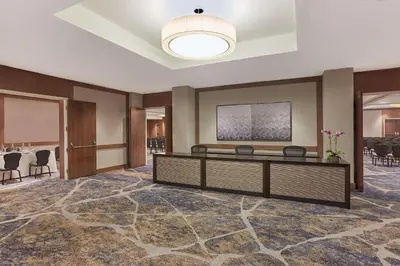 a large room with a waiting room with a table and chairs at Hyatt Regency Newport Beach West in Newport Beach