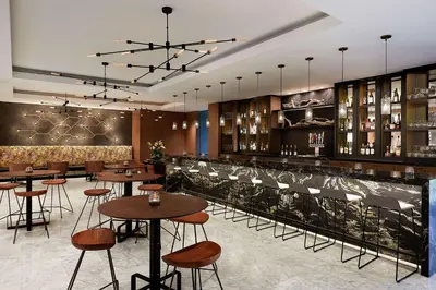 a restaurant with tables and chairs and a bar at Hyatt Regency Newport Beach West in Newport Beach