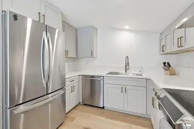 a kitchen with white cabinets and a stainless steel refrigerator at Beachfront feat Private Den SS166 in Solana Beach