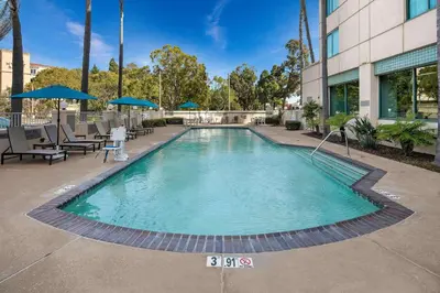 a pool with chairs and umbrellas next to a building at Country Inn & Suites by Radisson, San Diego North, CA in Mira Mesa