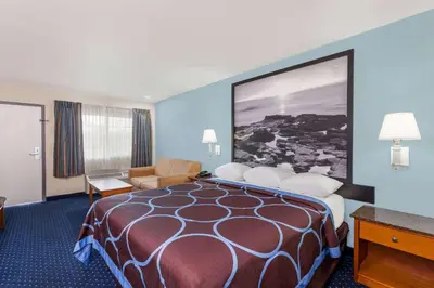a hotel room with a large bed and a chair at Super 8 by Wyndham El Cajon San Diego in El Cajon