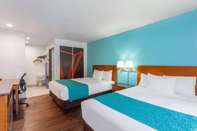 a hotel room with two beds and a desk at Howard Johnson by Wyndham National City/San Diego South in National City