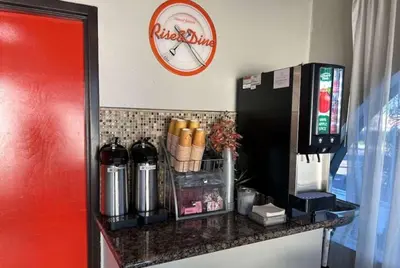 a counter with a refrigerator and a clock on the wall at Howard Johnson by Wyndham National City/San Diego South in National City