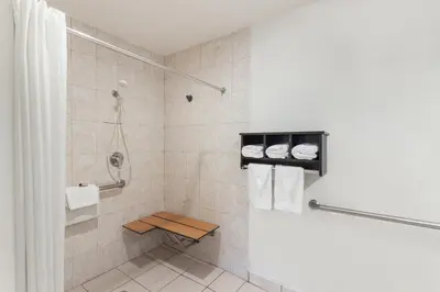 a bathroom with a shower with a bench in it at Howard Johnson by Wyndham National City/San Diego South in National City