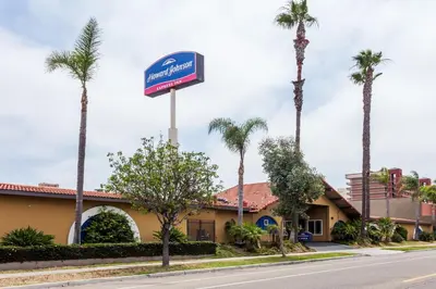 a sign in front of a hotel with palm trees at Howard Johnson by Wyndham National City/San Diego South in National City