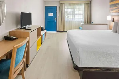 a room with a bed and a desk and a tv at Days Inn by Wyndham San Diego-East/El Cajon in El Cajon