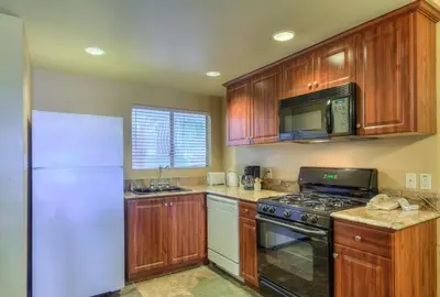 a kitchen with wooden cabinets and a white refrigerator at Oceanside Marina Suites - A Waterfront Hotel in Oceanside