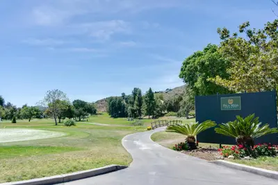 a winding road in a park with a sign and flowers at Pala Mesa Resort in Fallbrook