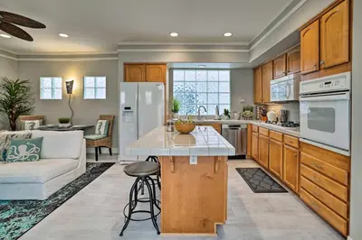 a kitchen with wooden cabinets and a white refrigerator at Oceanside Home with Rooftop Patio, Walk to Beach! in Oceanside