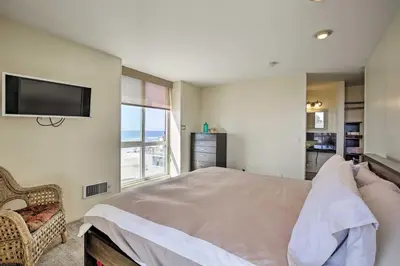 a bedroom with a bed and a tv on the wall at Beachfront Oceanside Condo with Pool and Hot Tub! in Oceanside