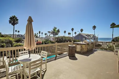 a patio with a table and umbrella and the ocean at Beachfront Oceanside Condo with Pool and Hot Tub! in Oceanside