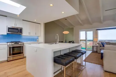 a kitchen with a large white island with black chairs at Beach Access Oceanview SBTC331 Condo in Solana Beach