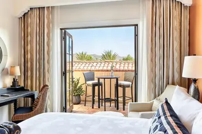 a bedroom with a bed and a balcony with a table and chairs at Inn at the Mission San Juan Capistrano, Autograph Collection in San Juan Capistrano