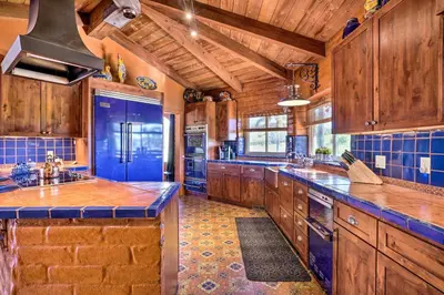 a large kitchen with wooden cabinets and blue tiles at Equestrian Estate with Horse Stables and Pool! in Valley Center
