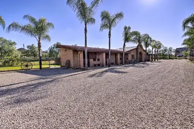 an empty road in front of a house with palm trees at Equestrian Estate with Horse Stables and Pool! in Valley Center