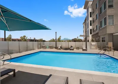 a swimming pool with chairs and a building at Hampton Inn & Suites El Cajon San Diego in El Cajon