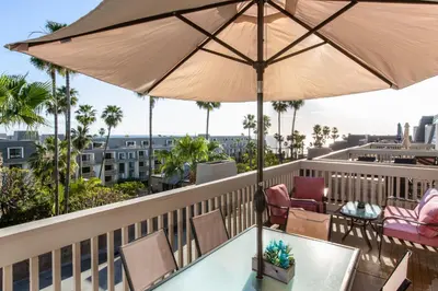 a balcony with a table and chairs and an umbrella at 3 Bedroom! - Complex is on the beach with huge pool in Oceanside