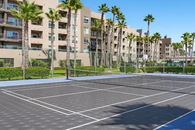 a tennis court in front of a building with palm trees at Worldmark Oceanside Harbor in Oceanside