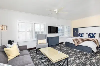 a bedroom with a bed and a couch and a tv at Hotel Marisol Coronado in San Diego