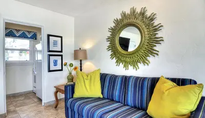 a living room with a blue and yellow couch and a mirror at Beachcomber Inn in San Clemente