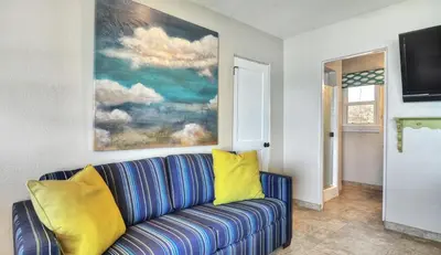a living room with a blue couch with yellow pillows at Beachcomber Inn in San Clemente