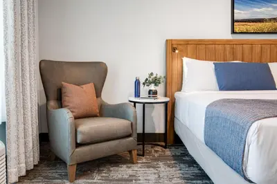 a bedroom with a bed and a chair next to a bed at Ayres Hotel Vista Carlsbad in Vista