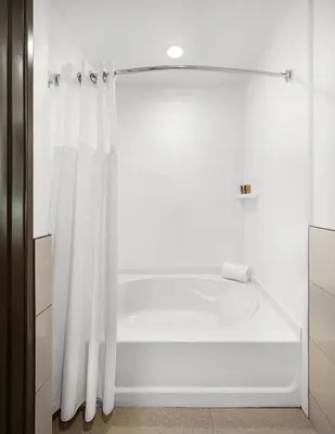 a bathtub with a shower curtain in a bathroom at Ayres Hotel Vista Carlsbad in Vista