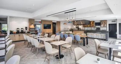 a restaurant with tables and chairs and a kitchen at Ayres Hotel Vista Carlsbad in Vista