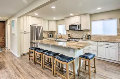 a kitchen with white cabinets and a large island with bar stools at Coastal Carlsbad Home 1 Mi to Beach and Downtown in Carlsbad
