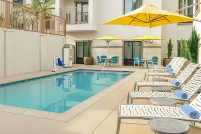 a pool with chairs and umbrellas next to a hotel at SpringHill Suites by Marriott San Diego Carlsbad in Carlsbad