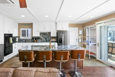 a kitchen with a large island with leather bar chairs at 128 Agate in Newport Beach