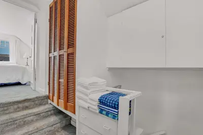 a white bedroom with a bed and towels on a shelf at 1106 Park Avenue in Newport Beach
